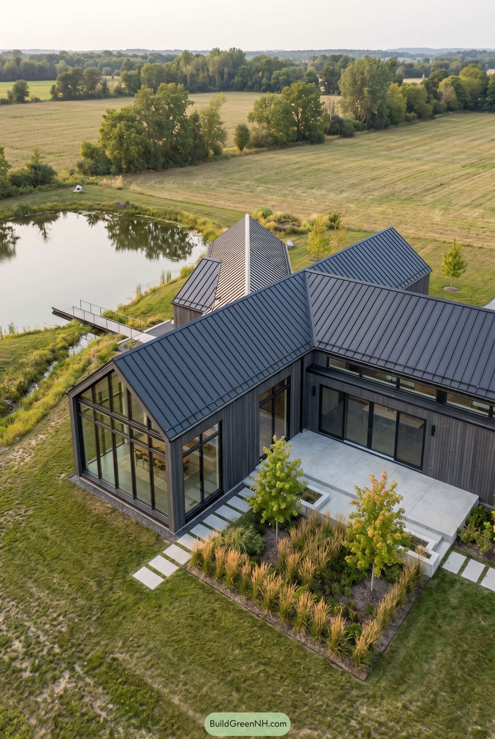 Modern black barnhouse with glass sunroom by pond