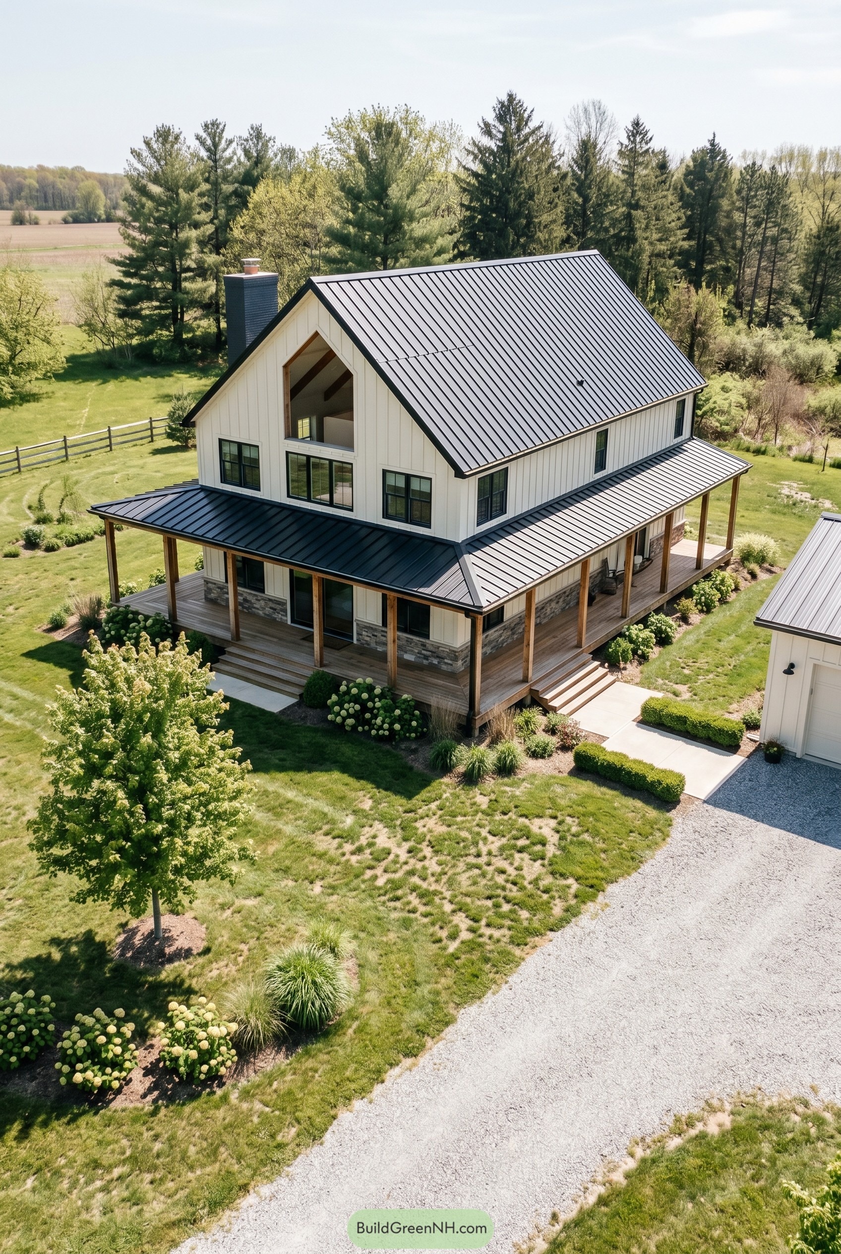 White barndominium with black metal roof and wraparound porch