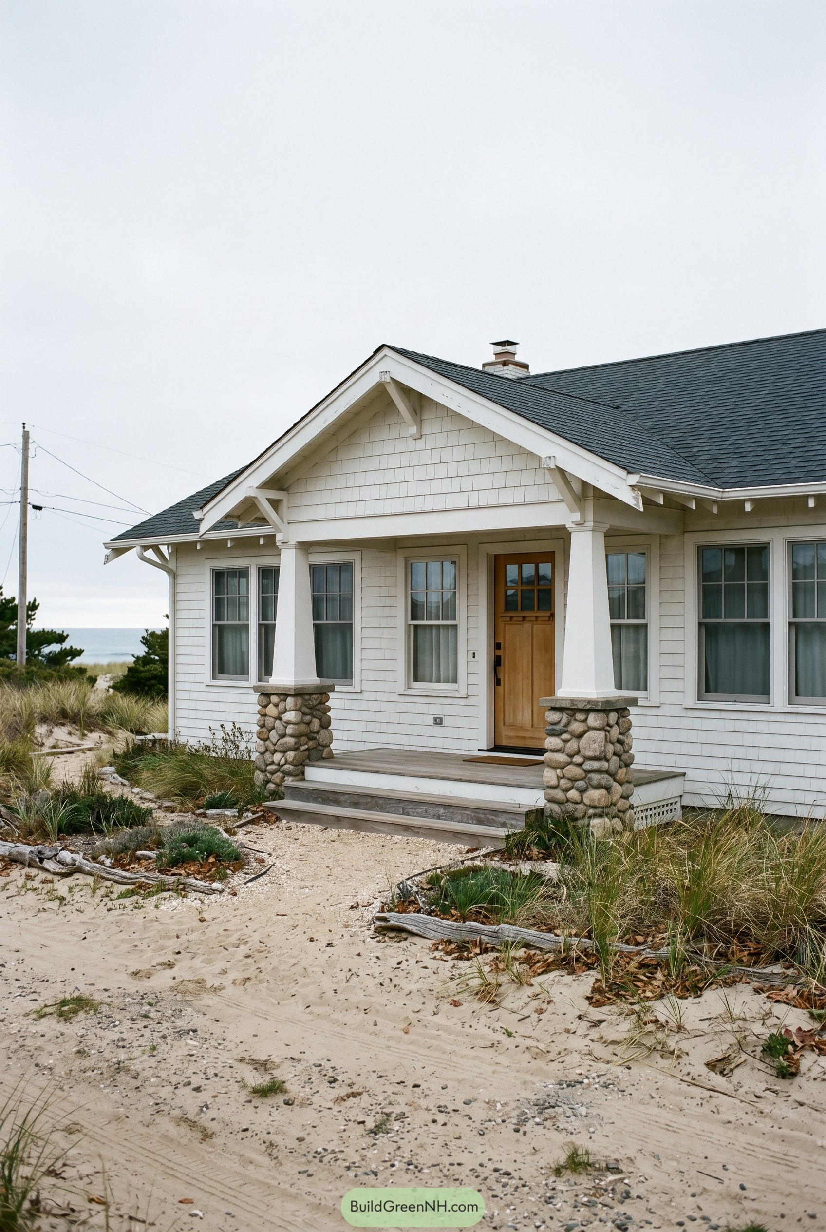 White craftsman bungalow with stone porch columns by dunes