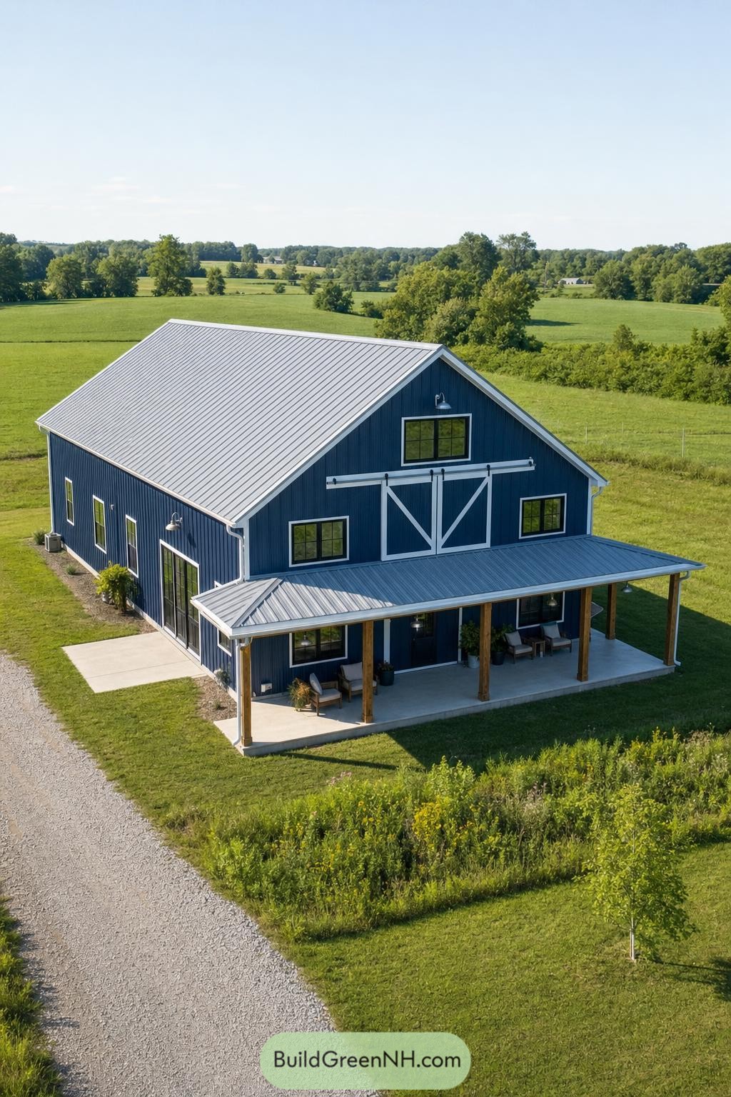Blue barndominium with a covered porch in green farmland