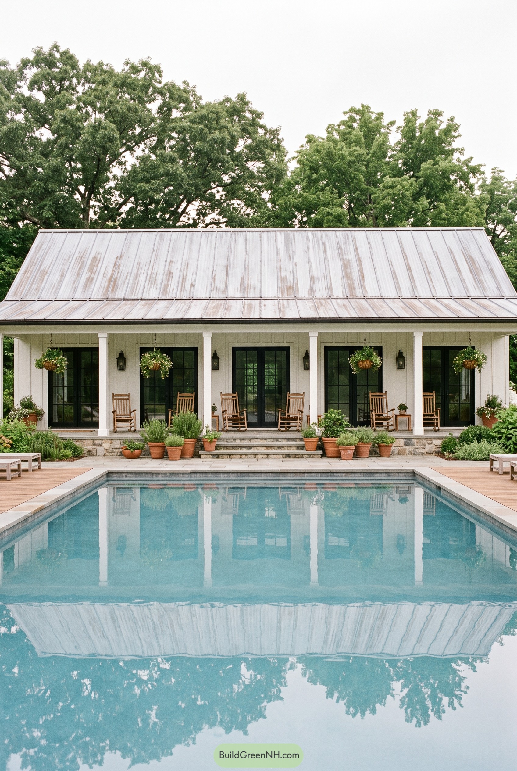 White farmhouse pool house with porch and pool