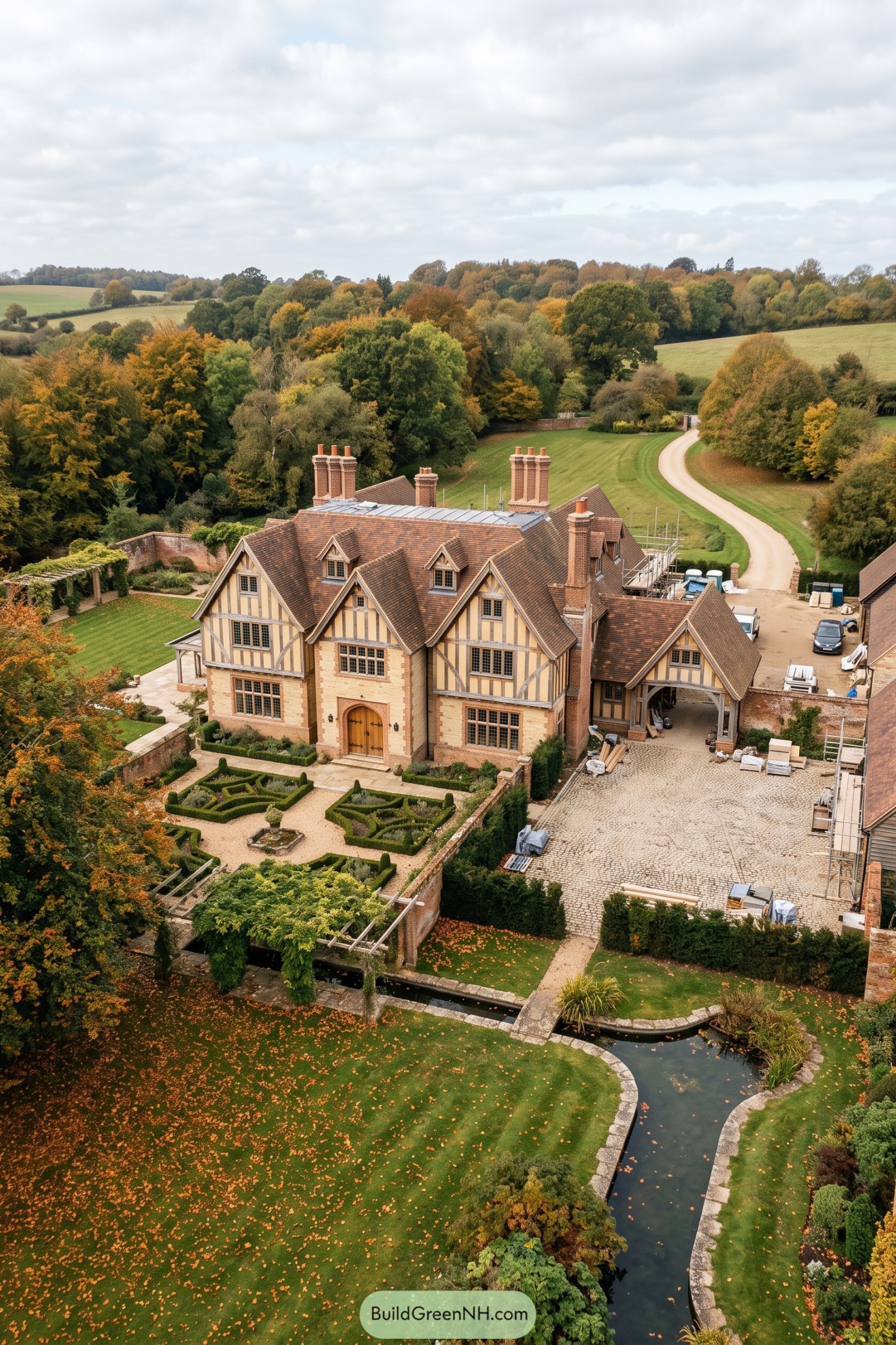 Aerial view of a Tudor revival estate with formal gardens and pond