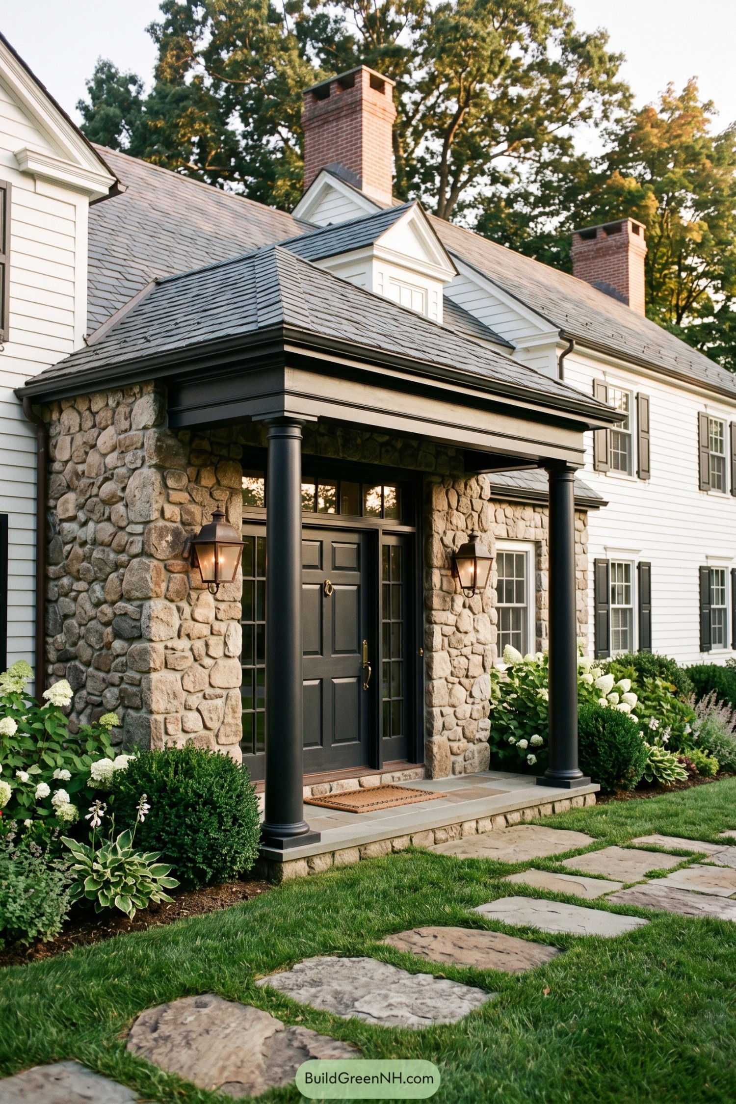 Fieldstone entry portico with black columns and white clapboard siding