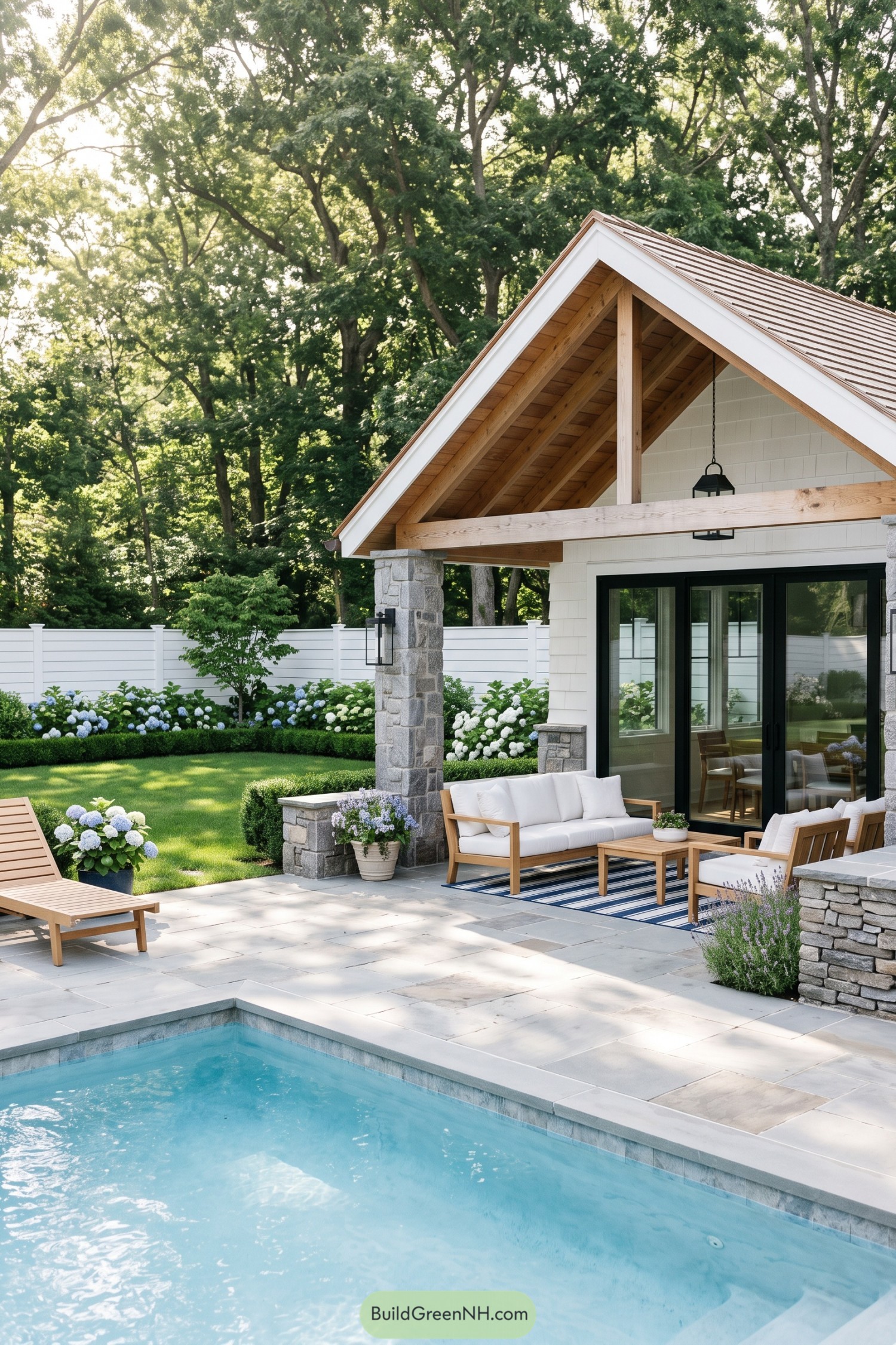 Gabled pool pavilion with stone columns and hydrangea beds