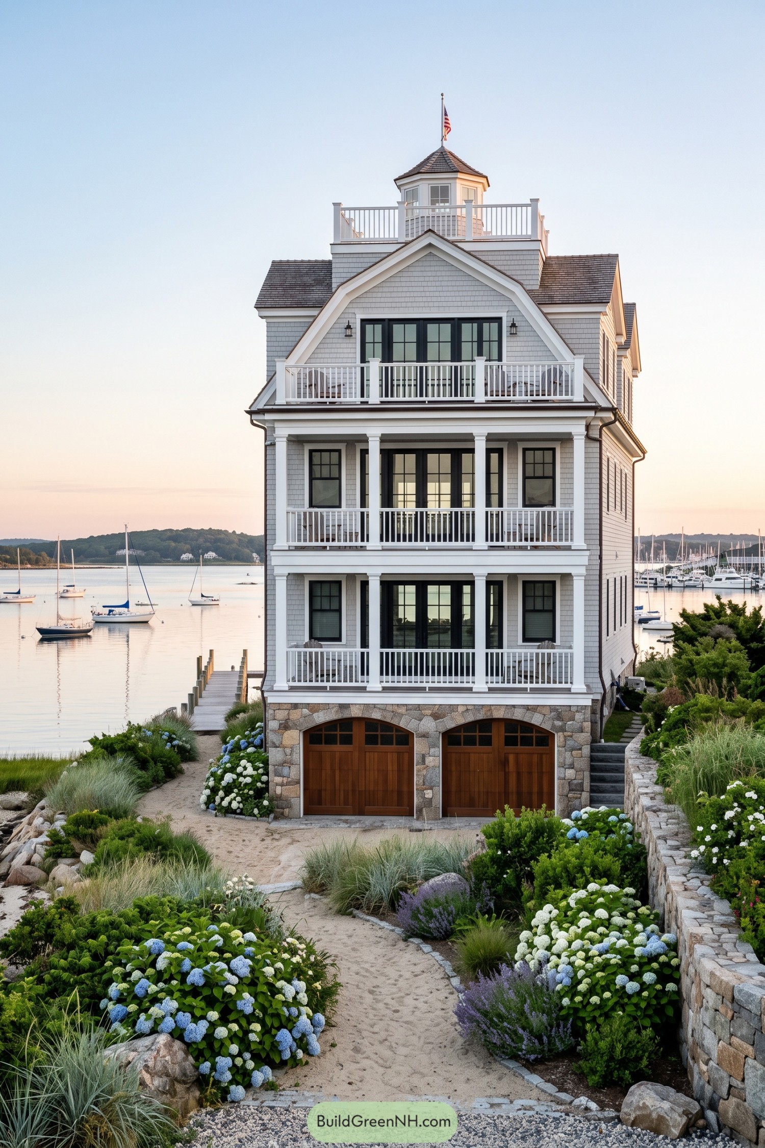 Three-story gray shingle waterfront home with porches and a cupola