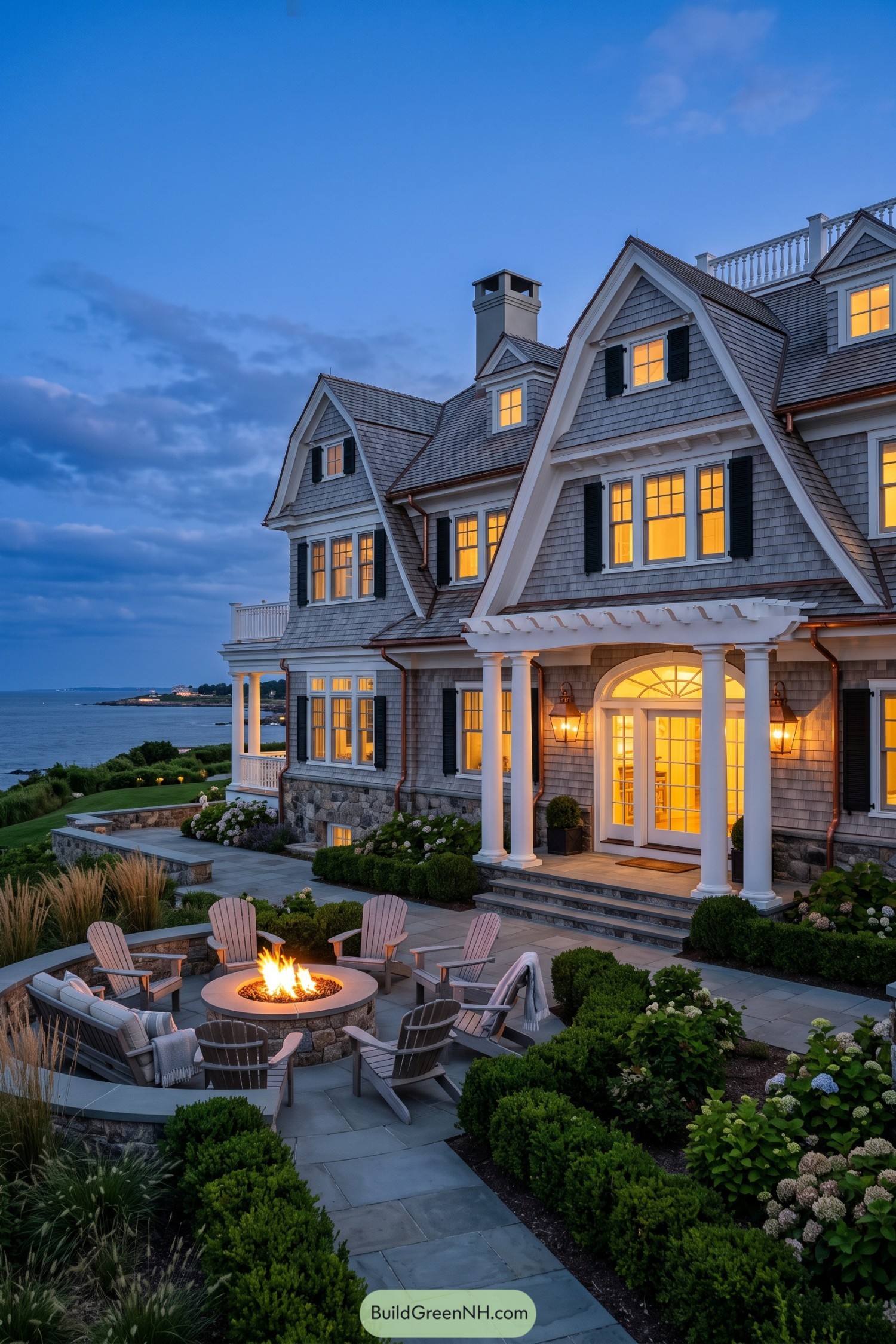 Gray shingle coastal home with columned entry and fire pit