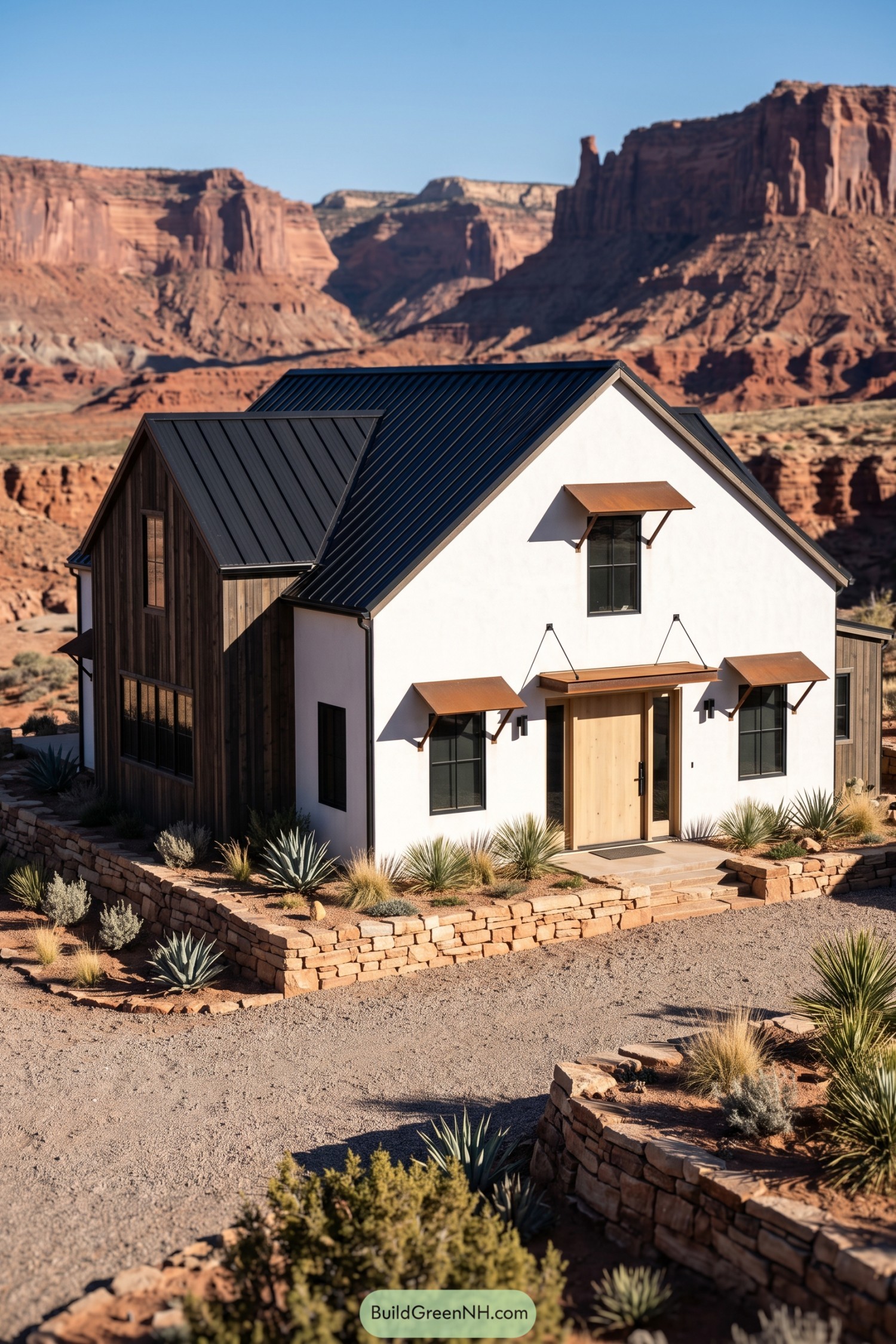 White modern barn house with black roof beside red canyon cliffs