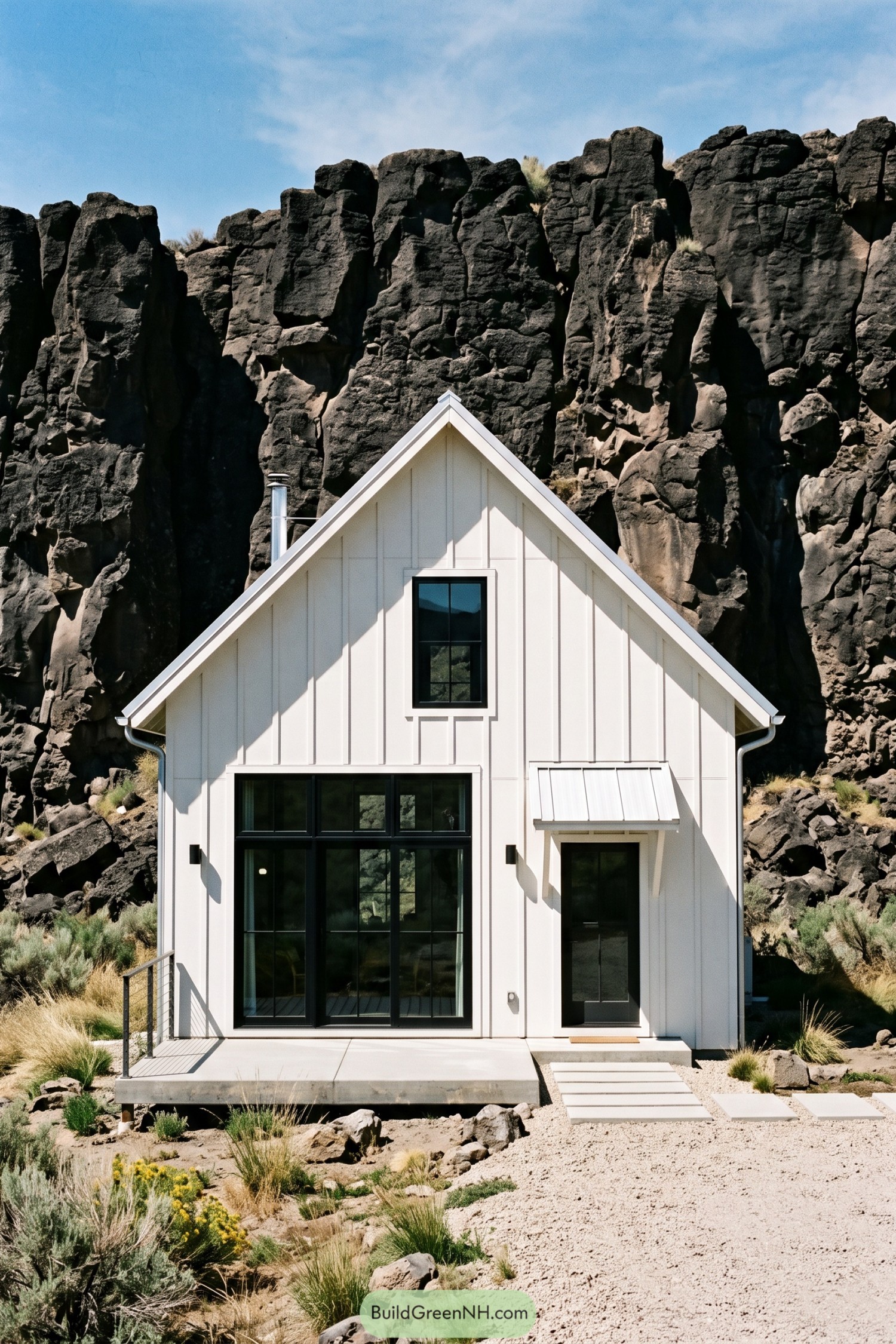 White gable barn house nestled beneath dark basalt cliffs