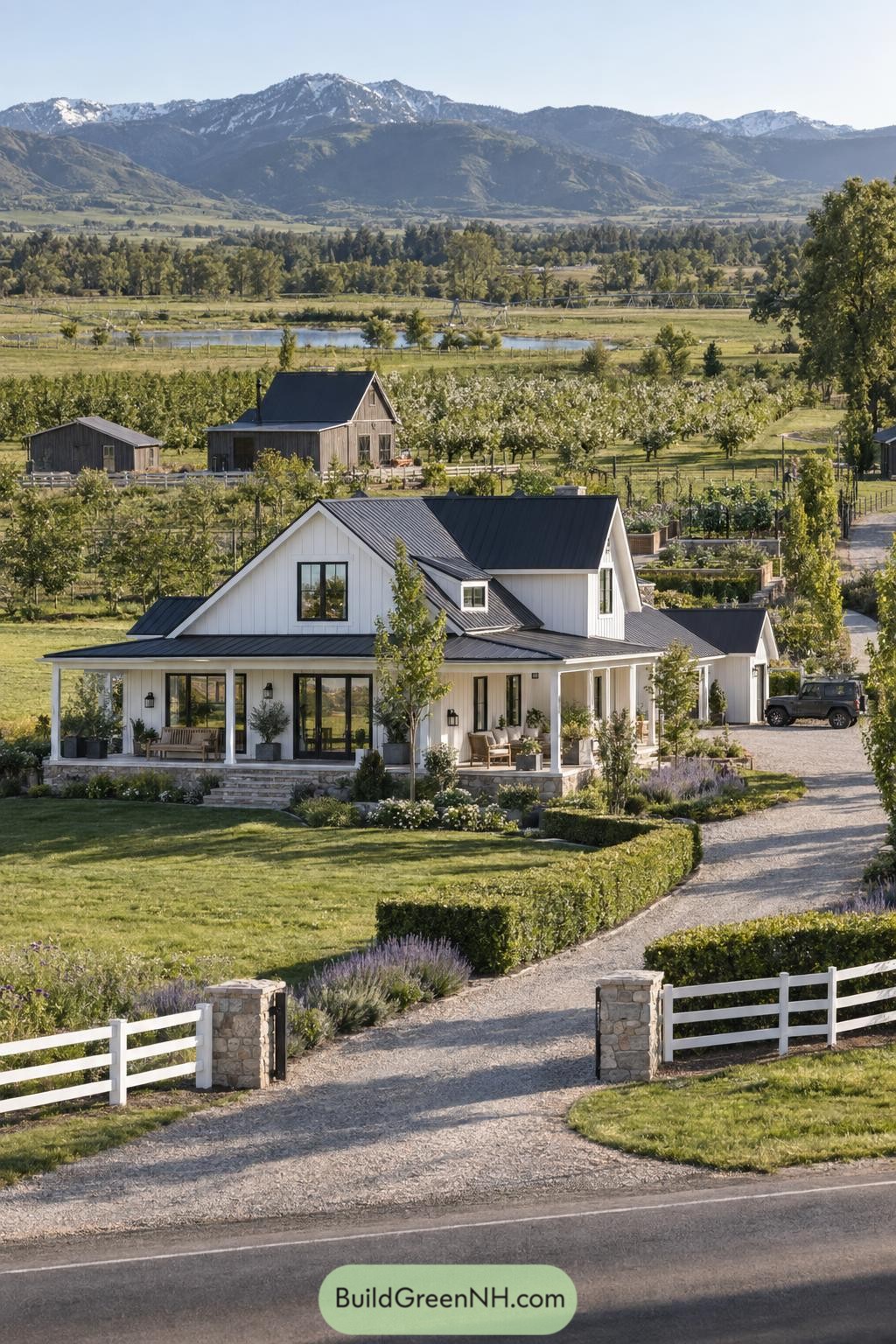 White farmhouse with black metal roof overlooking orchards and mountains