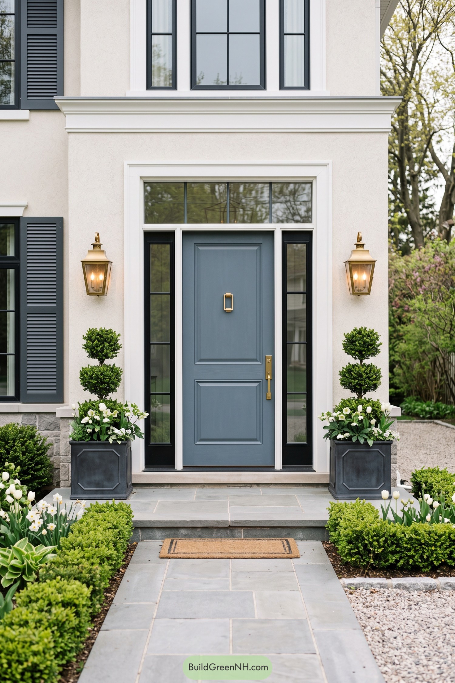 Steel blue paneled front door with black sidelights and brass lantern sconces