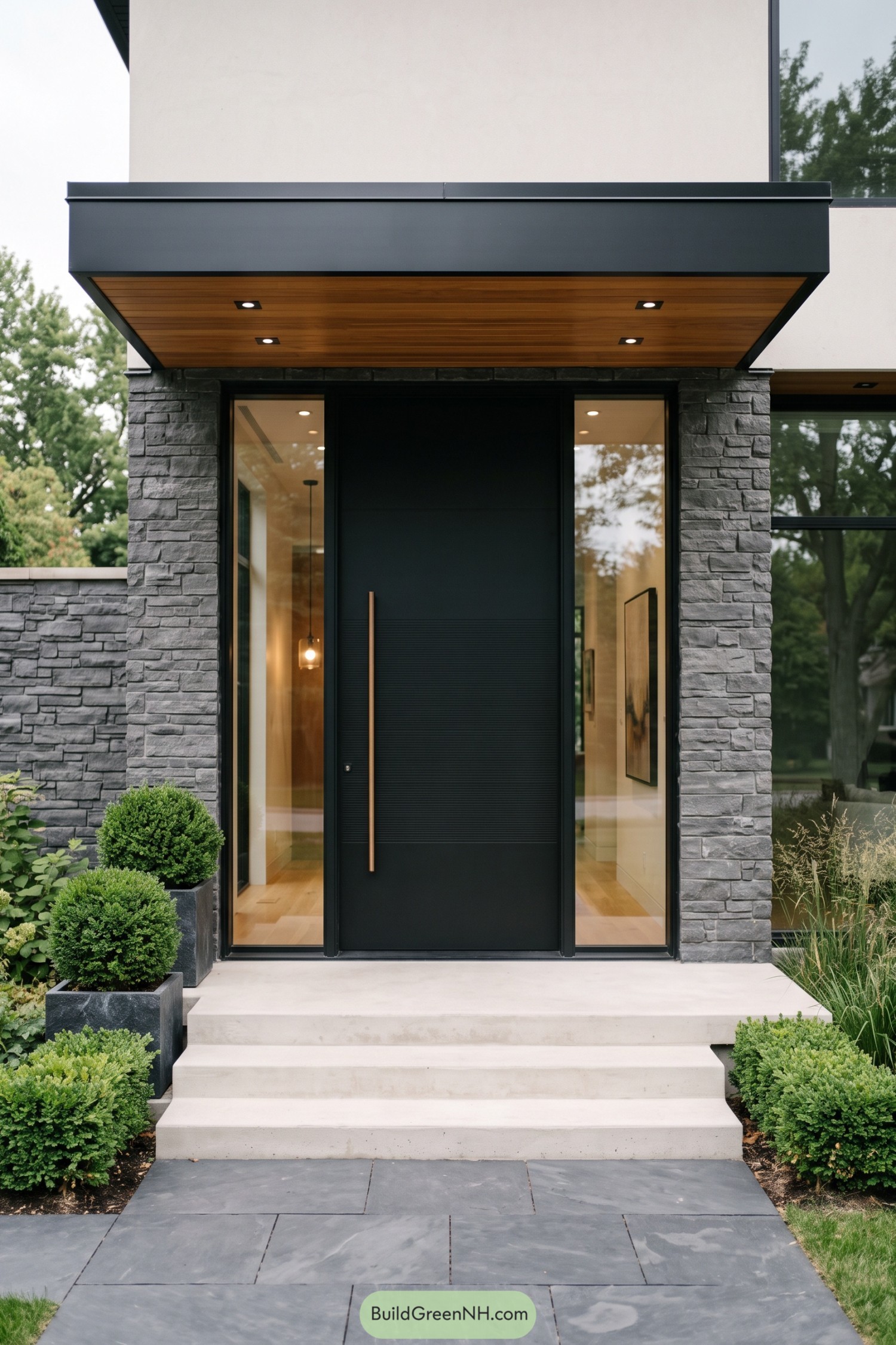Modern black entry door framed by glass sidelights and stacked stone