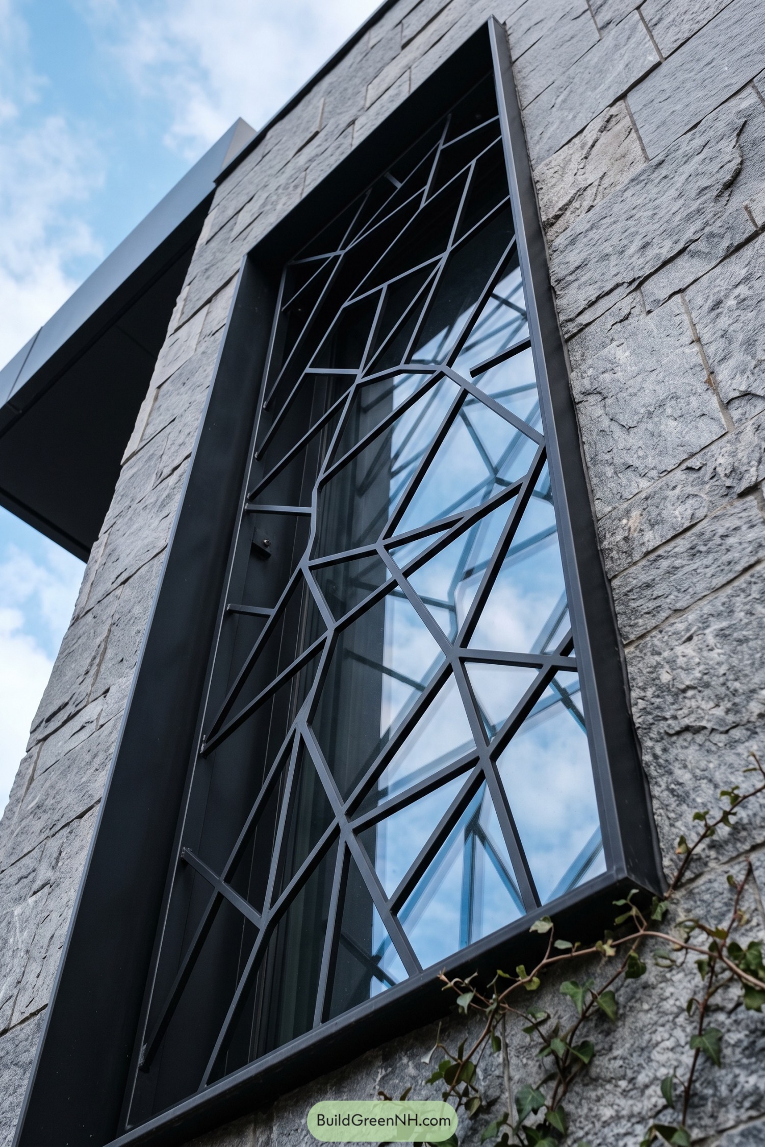 Black angular window grill on a tall stone-framed window