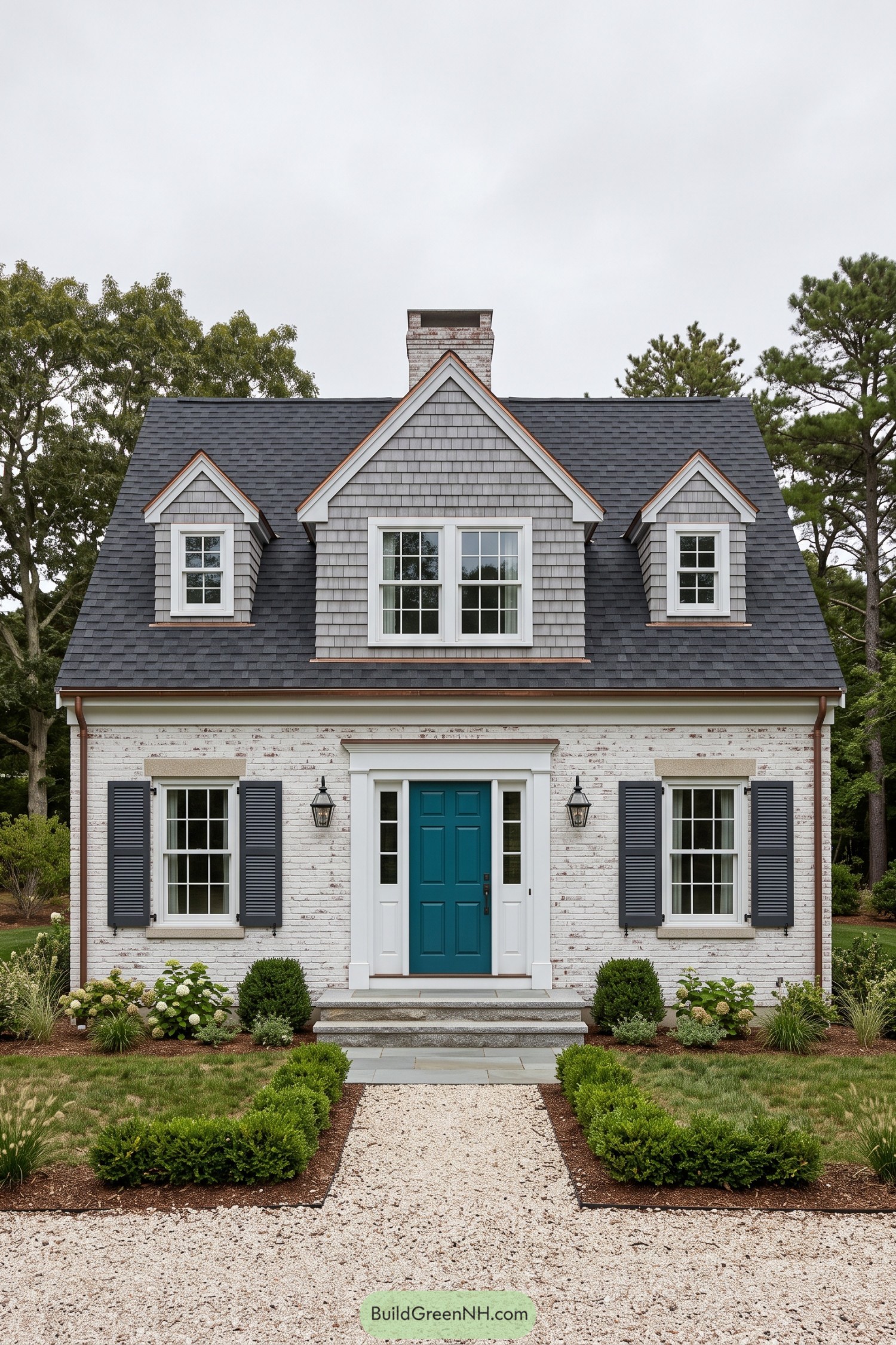 Cape Cod house with whitewashed brick, three gray shingled dormers, a teal door, and neatly bordered gardens
