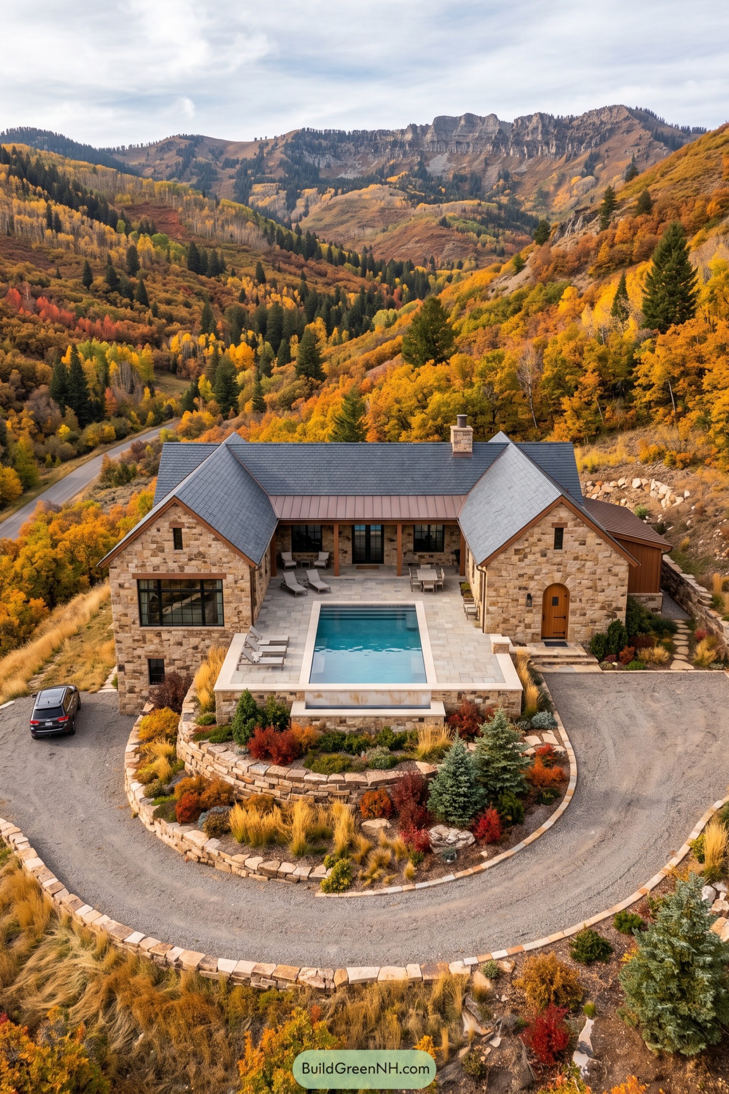 Stone cabin with twin gabled wings framing a rectangular pool and landscaped terraces on an autumn mountainside